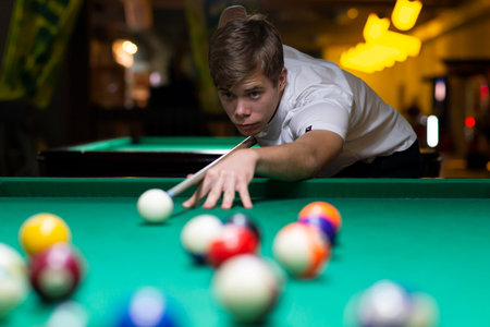 Handsome young man playing pool in pub