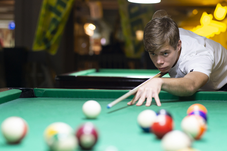 Handsome young man playing pool in pubの販売画像
