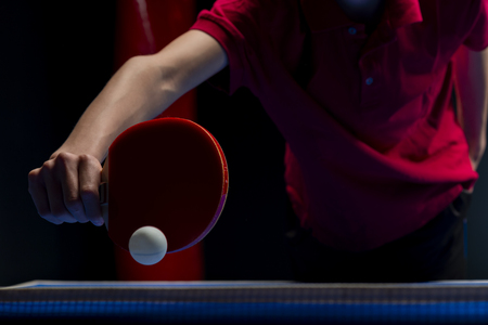 Table tennis ping pong paddles and white ball on blue boardの写真素材
