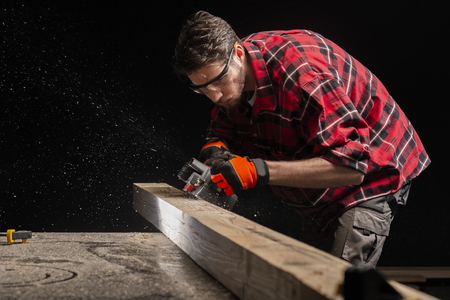 Carpenter works with electrical planer in workshopの写真素材