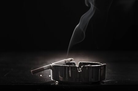 Closeup of cigarette on ashtray with a beautiful wisp of smokeの写真素材
