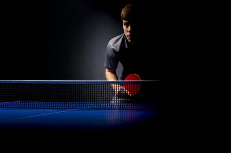 Portrait of young man playing tennis on black backgroundの写真素材