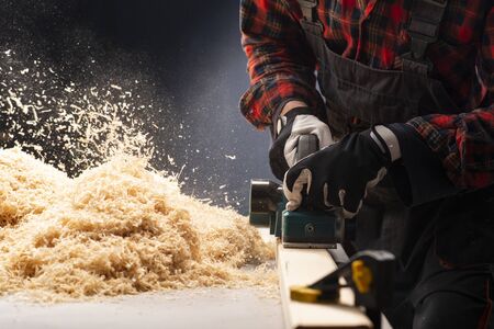Carpenter works with electrical planer in workshop.Manufacture of wood products. Carpentry workshopの写真素材