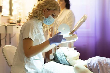 Spa, resort, beauty and health concept - beautiful woman in spa salon getting face treatment. Face skin care. Cosmetology の写真素材