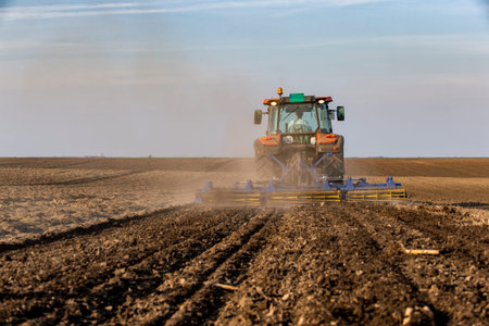 Tractor working in the field, preparing the land for planting,  working plowed field