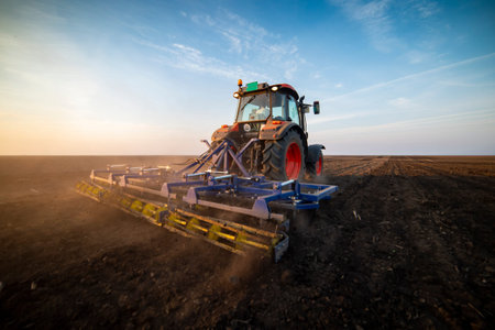 Tractor working in the field, preparing the land for planting,  working plowed field