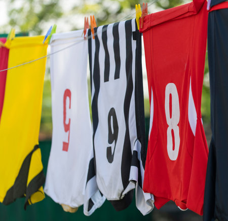 Colorful clothes hanging to dry on a laundry line. Football jerseys