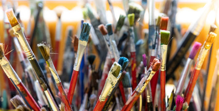 A lot dirty artist paint brushes in a bucket. Different artist brushes, close-up view