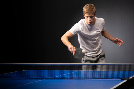 Portrait of young man playing tennis on black backgroundの写真素材