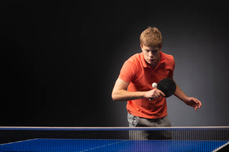 Portrait of young man playing tennis on black backgroundの写真素材