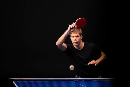 Portrait of young man playing tennis on black backgroundの写真素材