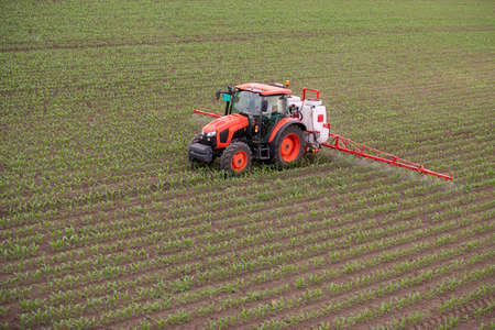 Tractor spray fertilize field with insecticide herbicide chemicals in agriculture fieldの写真素材