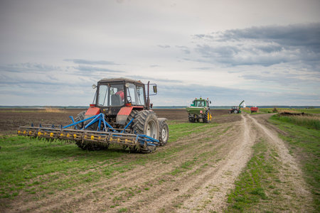 Three tractors working in the field, preparing the land for planting,  working plowed field