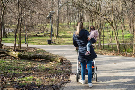 A mother holds her daughter in her arms as she walks in the parkの写真素材