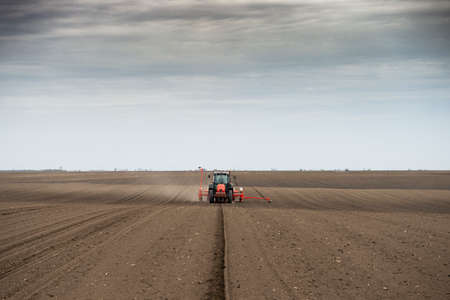 Farmer with tractor seeding - sowing crops at agricultural fields in springの写真素材