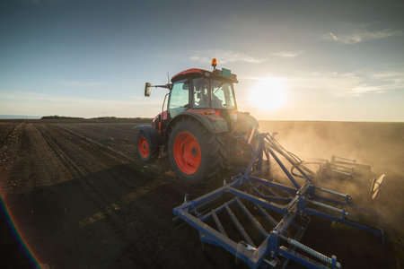 Tractor working in the field, preparing the land for planting,  working plowed field