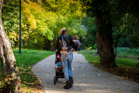A young mother walks with her children through the park