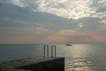 A boat in the distance at sea and an entrance to the sea with a handrail. Umag, Istrian Peninsula, Croatiaの写真素材
