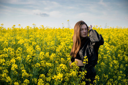 Young woman in a field of oil rapeseed in bloom in sunset. Ecology