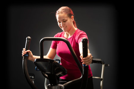 Young woman training nordic skiing in the gym on black background