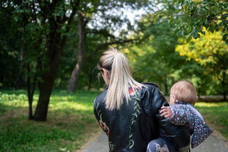A mother holds her daughter in her arms as she walking by rural road in forestの写真素材