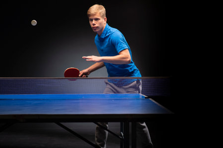 Portrait of young man playing tennis on black backgroundの写真素材