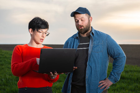A woman agronomist and a young farmer examine planted young wheat in the springの写真素材