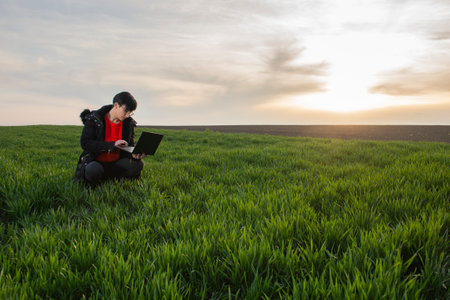 A woman agronomist examines planted young wheat in the springの写真素材