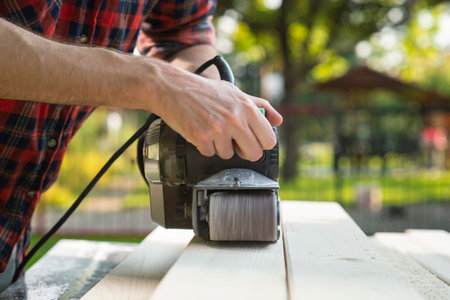 The carpenter works with the electric polisher on the woodの写真素材