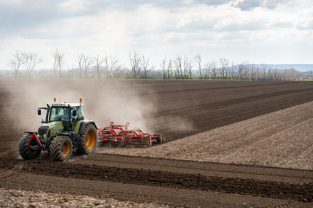 Tractor working in the field, preparing the land for planting,  working plowed fieldの写真素材
