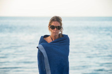 A woman wrapped in a blue towel after swimming in the seaの写真素材