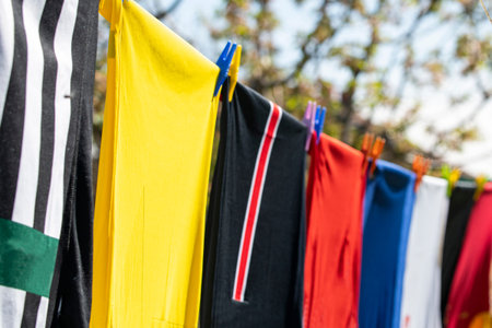Colorful clothes hanging to dry on a laundry line. Football jerseys