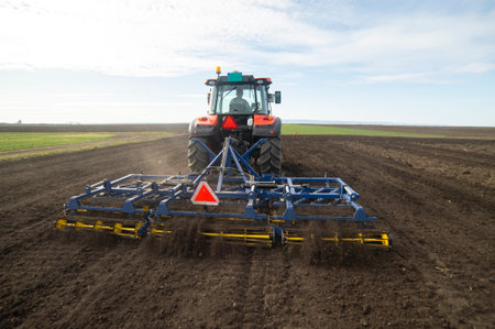 Tractor working in the field, preparing the land for planting,  working plowed field