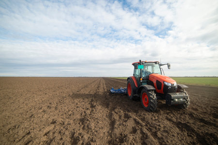 Tractor working in the field, preparing the land for planting,  working plowed field