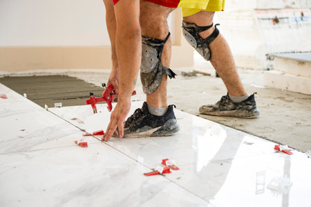 Ceramic tiles. Ceramic white floor tiles laid over adhesive with a tile leveling systemの写真素材