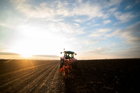 Tractor working in the field, preparing the land for planting,  working plowed fieldの写真素材