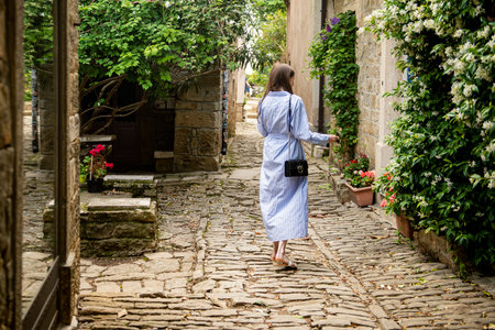 A young woman walks down a small, cobbled street in a beautiful, small town on the Istrian...