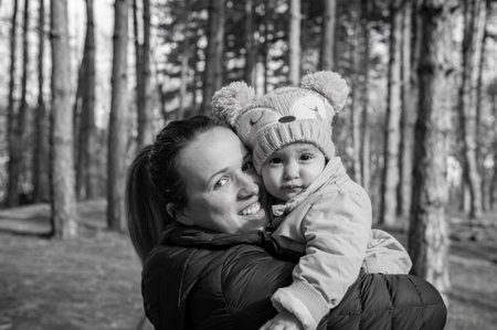 A mother holds her daughter in her arms while walking along a country road in the forest. Black and whiteの写真素材