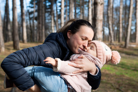 A mother holds her daughter in her arms while walking along a country road in the forestの写真素材