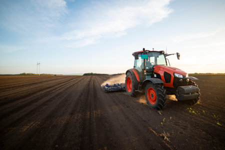 Tractor working in the field, preparing the land for planting,  working plowed field