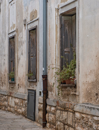 Old rustic house facade with massive wooden shutters on the windows and flowers.の写真素材