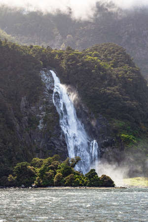 Fiordland National Park. Waterfall on the background of a green mountain. South Island, New Zealandの写真素材