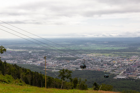 Cable car on the top of the mountain with the city in the background. Cableway in Yuzhno-Sakhalinsk. Ski Trail - Height. Sakhalin, Russiaの写真素材