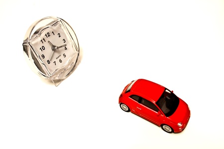 Red toy car with clock on white isolated backgroundの写真素材