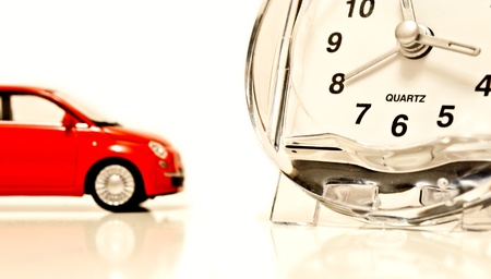 Red toy car with clock on white isolated backgroundの写真素材
