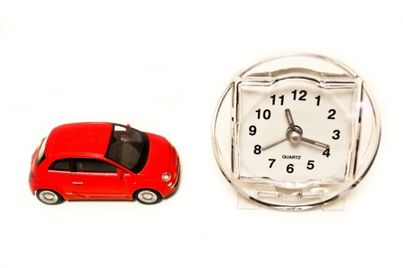 Red toy car with clock on white isolated backgroundの写真素材