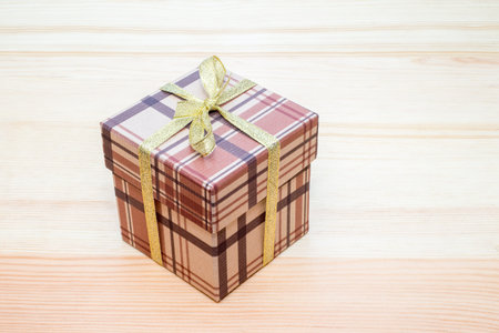 brown gift box with bow on wooden table