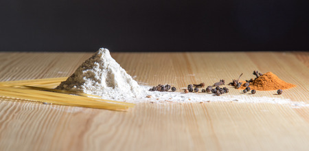 still life: hill of flour, spices and spaghetti on the wooden tableの写真素材
