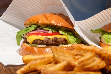 fresh burgers and fries on a wooden trayの写真素材