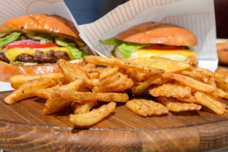 fresh burgers and fries on a wooden trayの写真素材